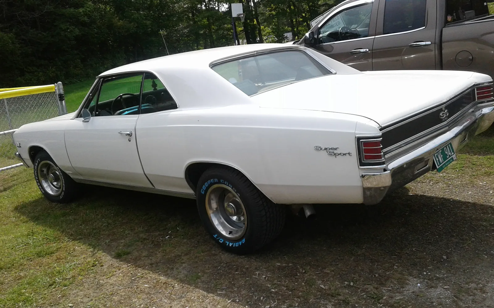 A white 1967 Chevrolet Malibu Super Sport viewed in three-quarter perspective, parked at a classic car show